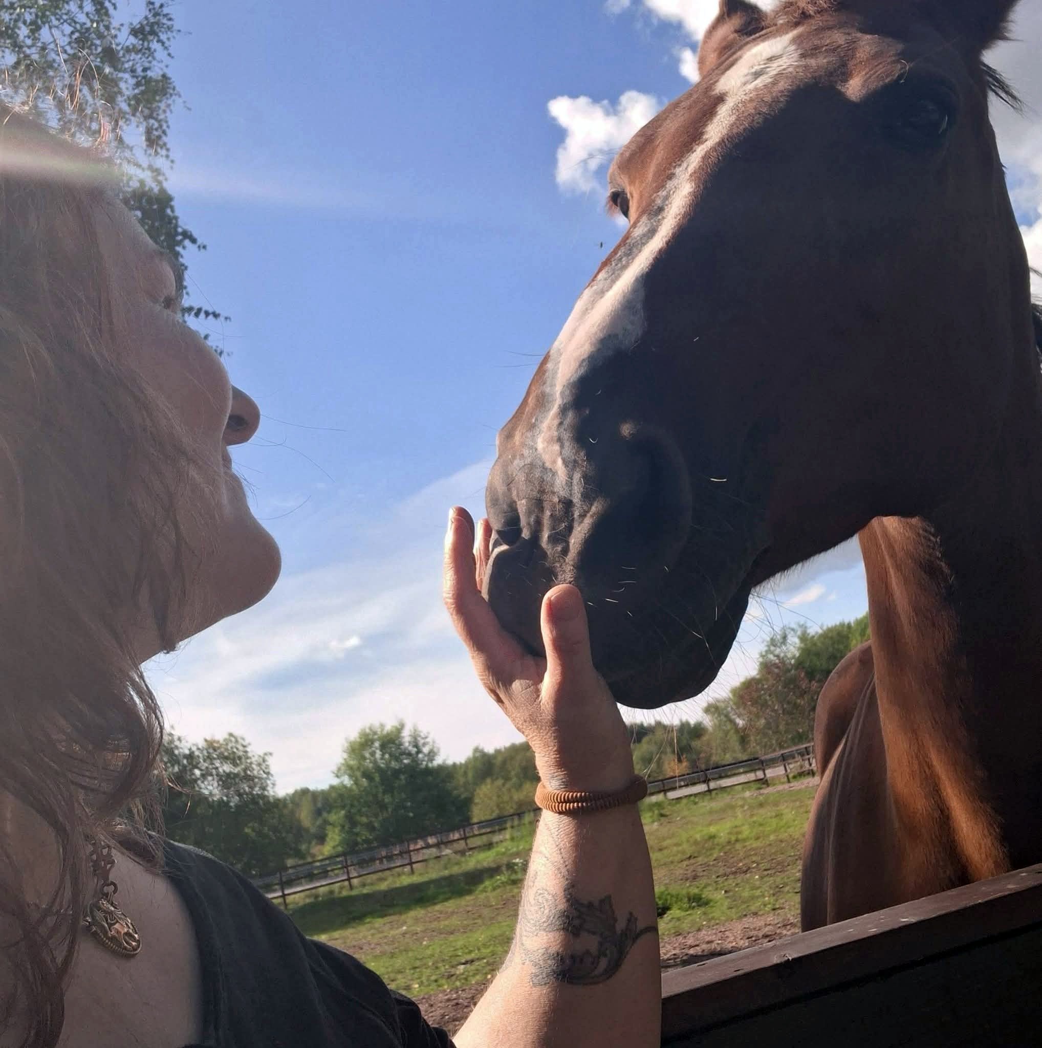 Annica klappar en hästs mule utomhus